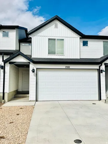 View of front of home with board and batten siding, a garage, and concrete driveway