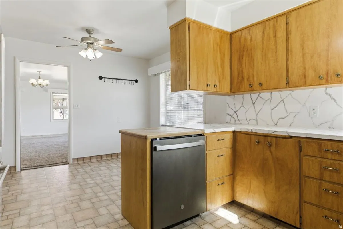 Kitchen featuring dishwasher, ceiling fan, decorative backsplash, wood finish cabinets, and hanging lights