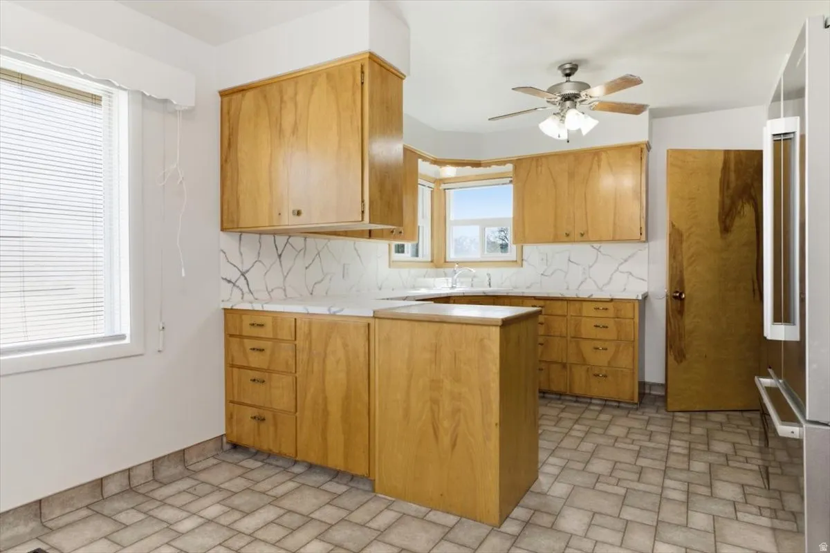 Kitchen featuring light countertops, a peninsula, high end fridge, decorative backsplash, and ceiling fan
