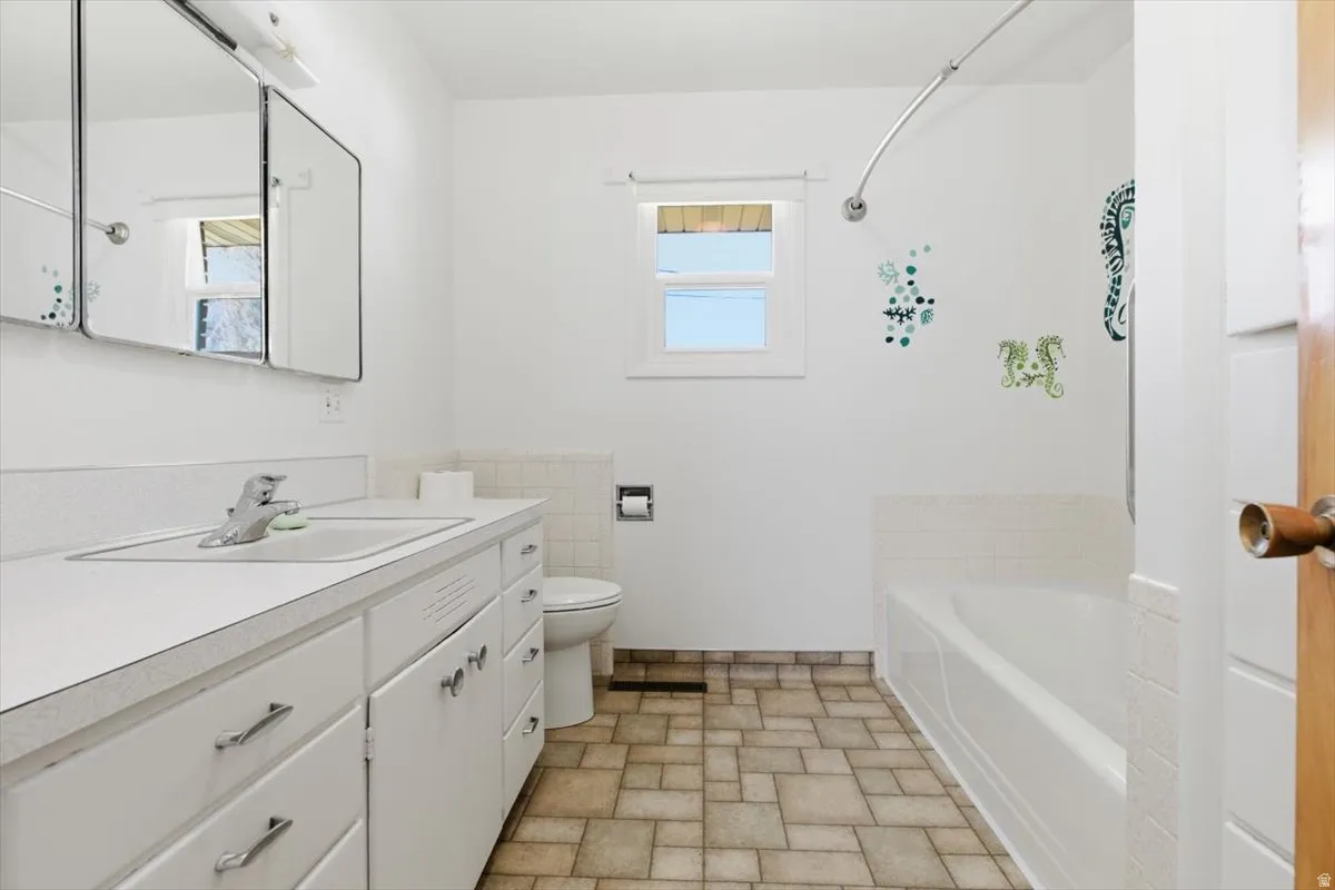 Bathroom featuring vanity, washtub / shower combination, and stone finish flooring
