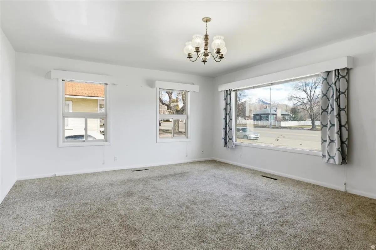 Empty room with a chandelier and carpet floors