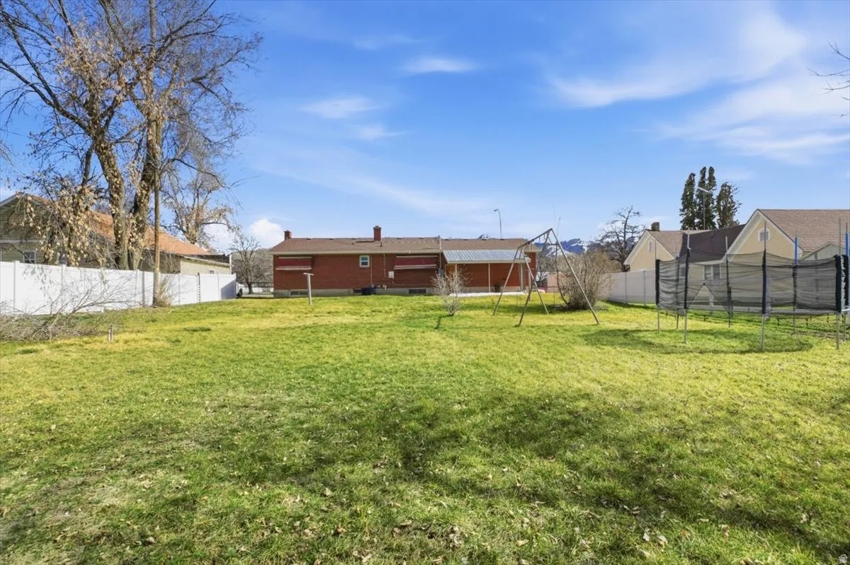 Rear view of property featuring a trampoline and a fenced backyard