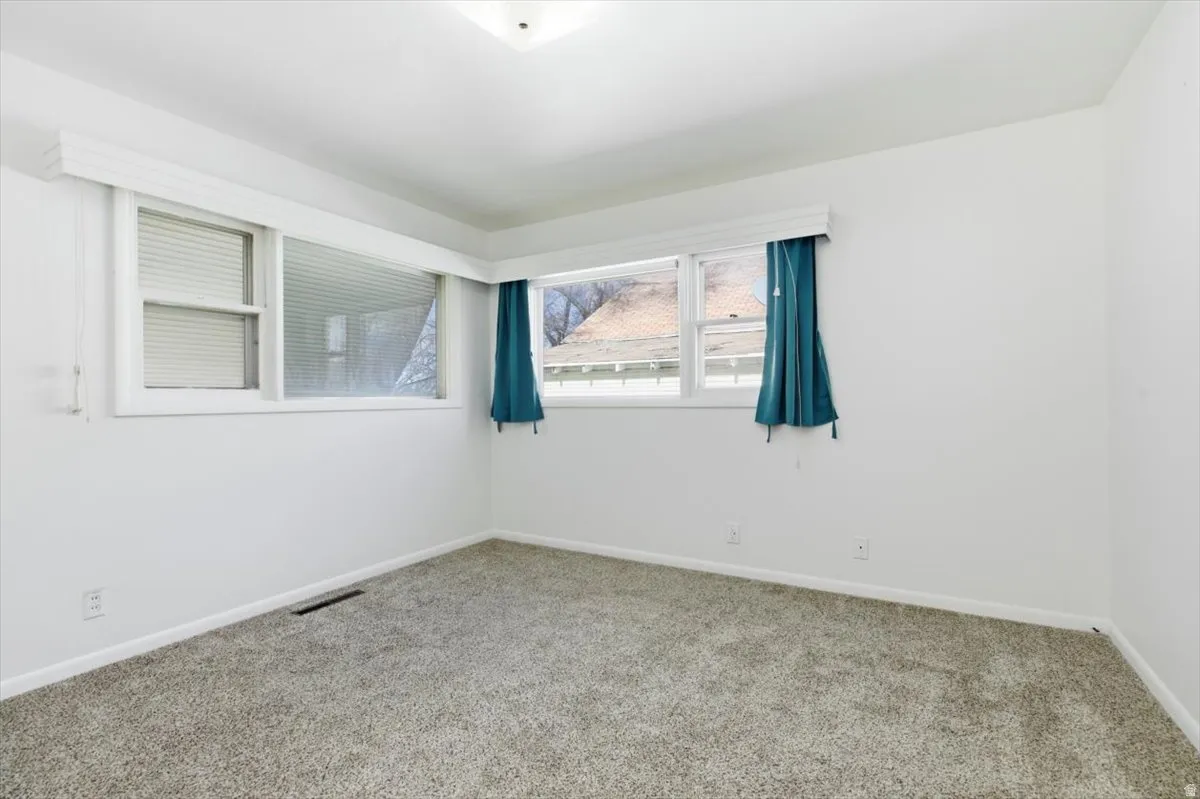 Carpeted spare room featuring baseboards