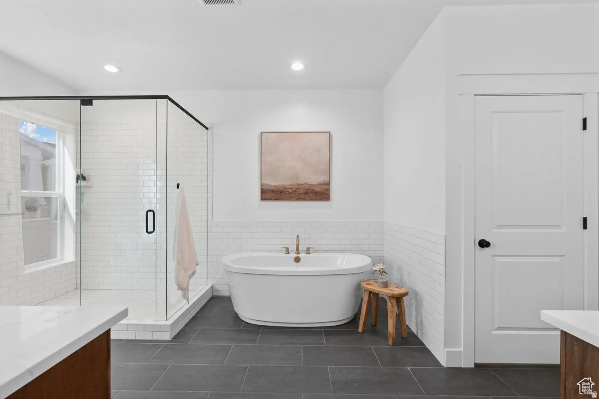 Full bathroom with vanity, tile walls, a wainscoted wall, a freestanding bath, and a stall shower