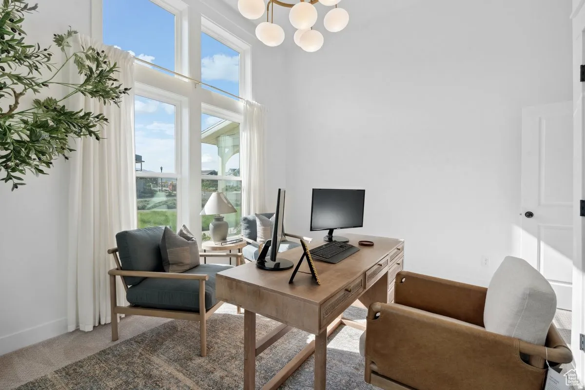 Carpeted office featuring a high ceiling and hanging lights