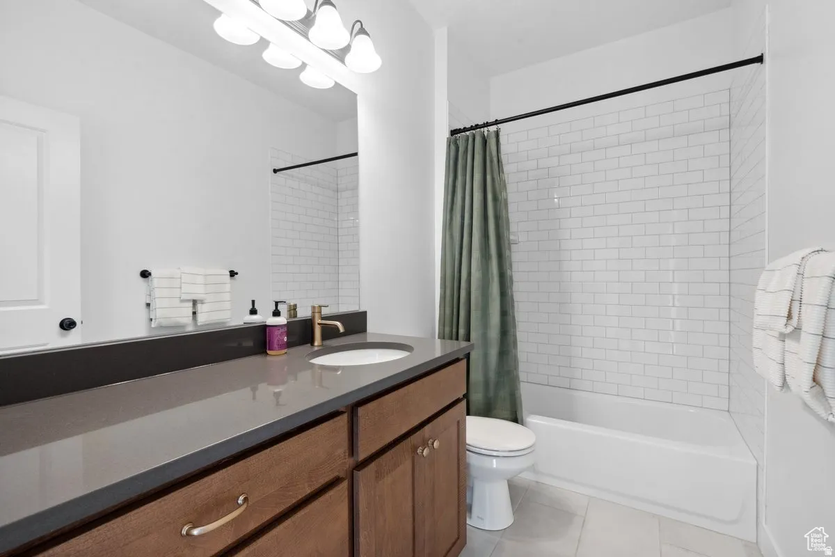 Full bathroom featuring vanity, shower / bathtub combination with curtain, and light tile patterned flooring