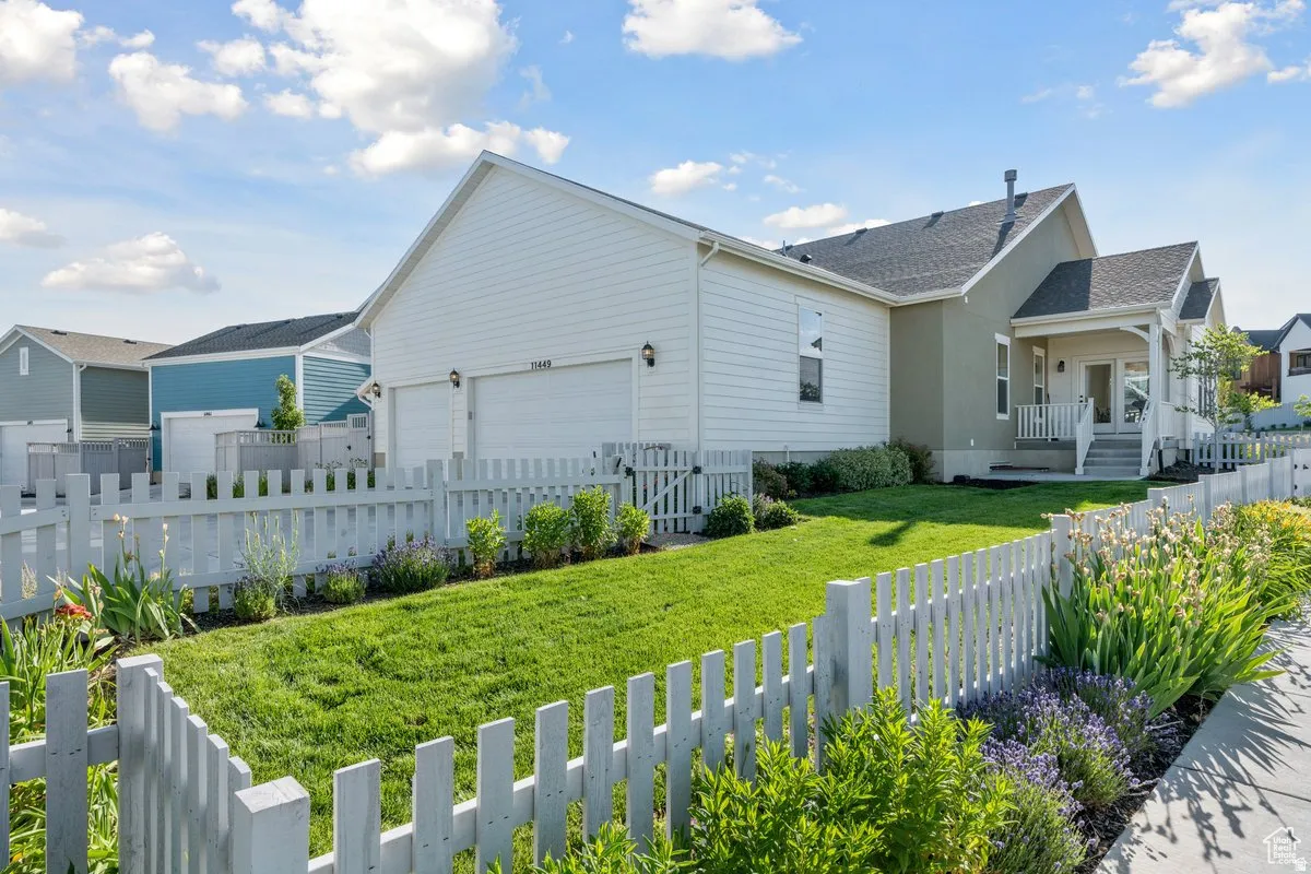 View of side of property featuring a fenced front yard, an attached garage, covered porch, and a shingled roof