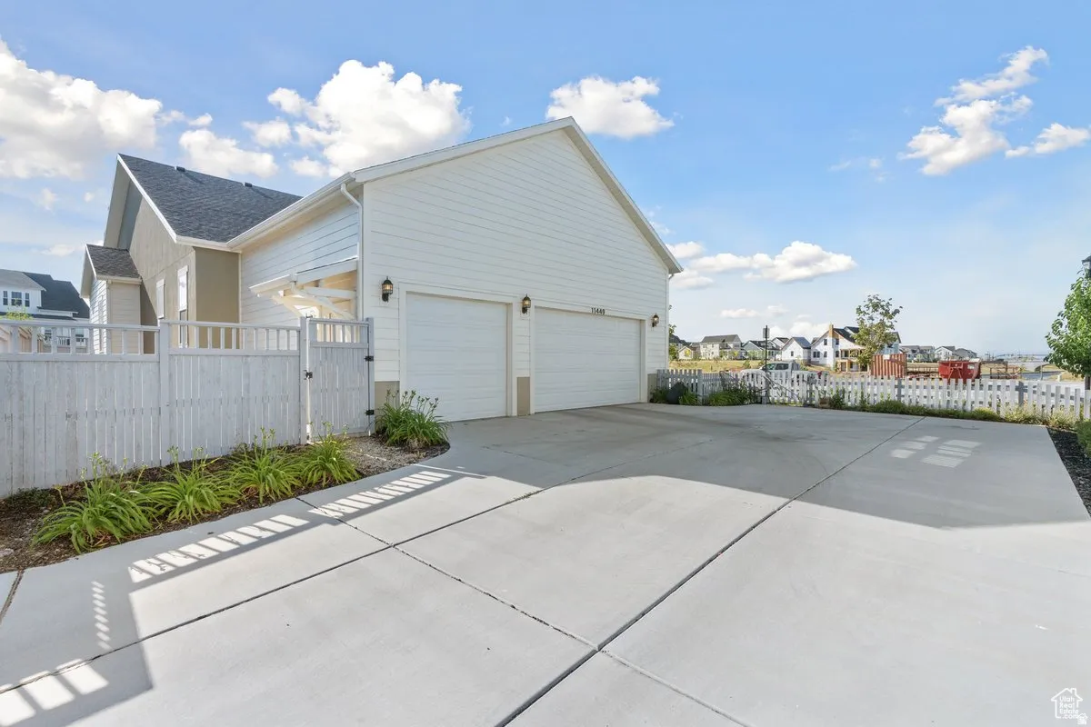 Garage with a residential view, a gate, and concrete driveway