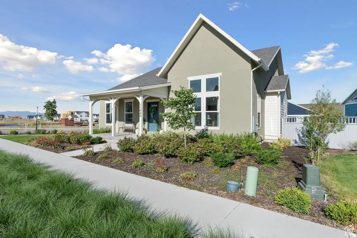 View of front of house with a porch, stucco siding, and a shingled roof