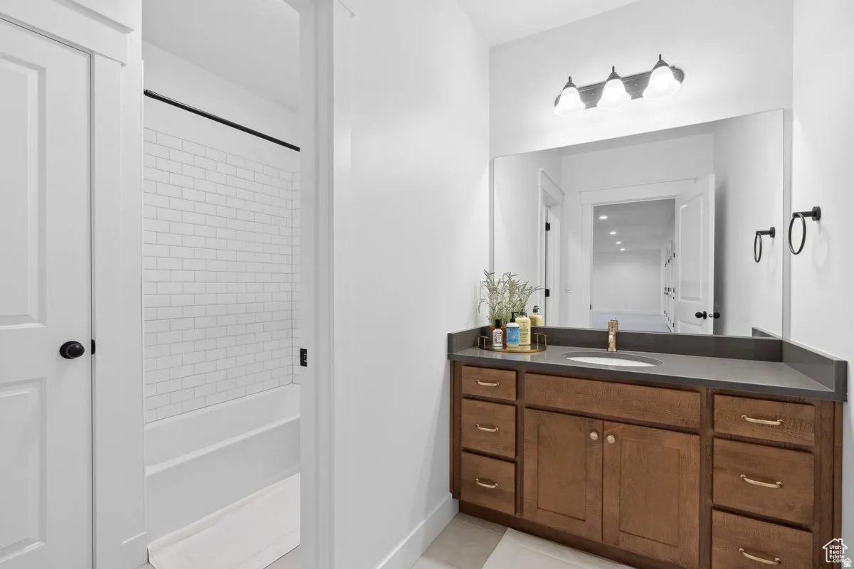 Full bathroom featuring vanity, light tile patterned flooring, and washtub / shower combination
