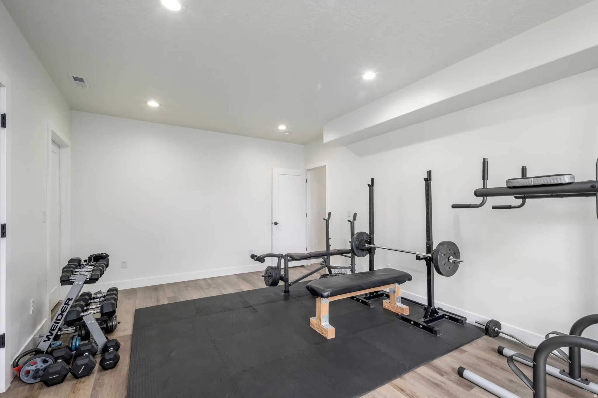 Exercise area with light wood-style floors and recessed lighting
