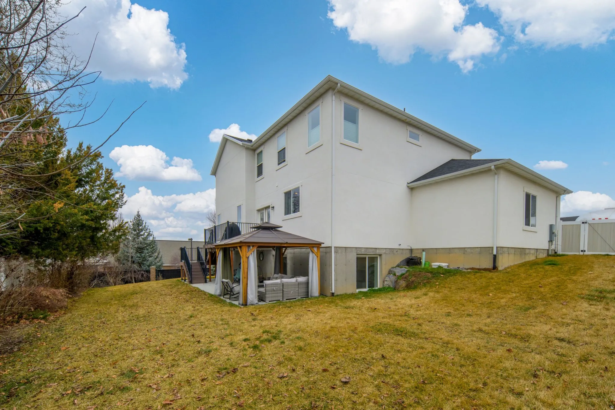 Back of house with a patio, a gazebo, a fenced backyard, an outdoor living space, and a gate