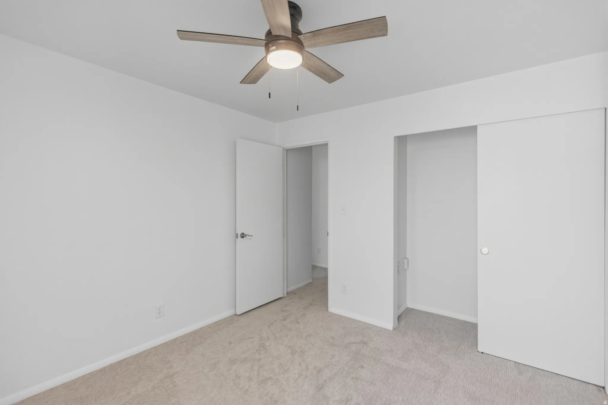 Unfurnished bedroom featuring light carpet, ceiling fan, and a closet