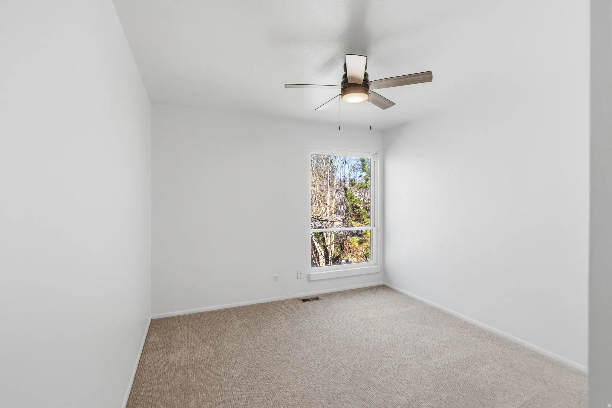Carpeted empty room with a ceiling fan and baseboards