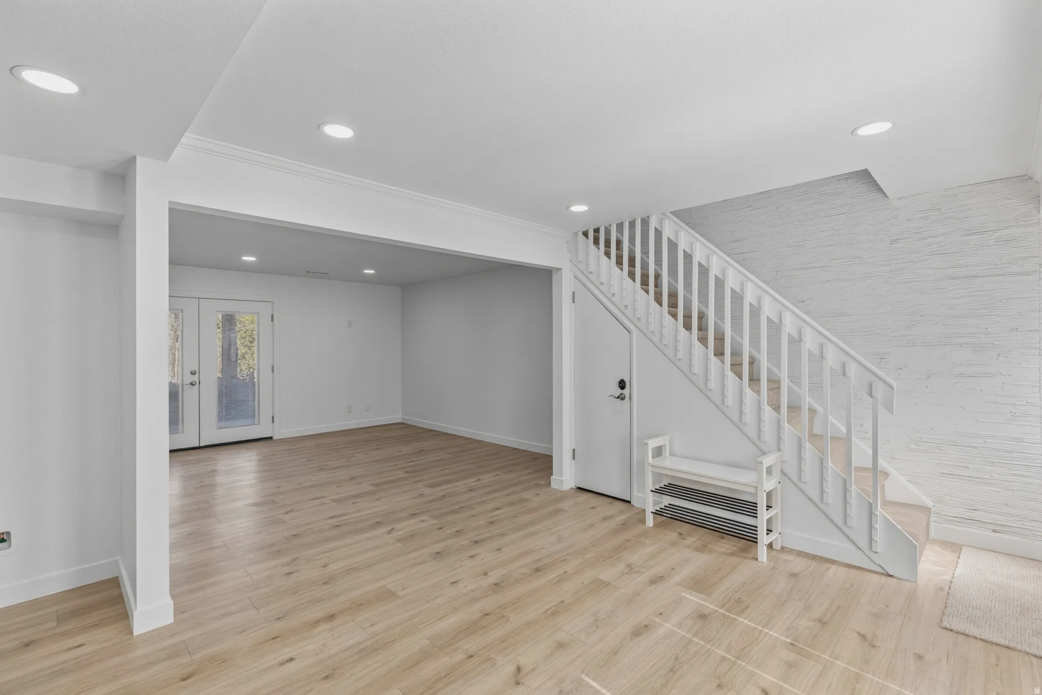 Below grade area featuring light wood-style floors, french doors, and recessed lighting