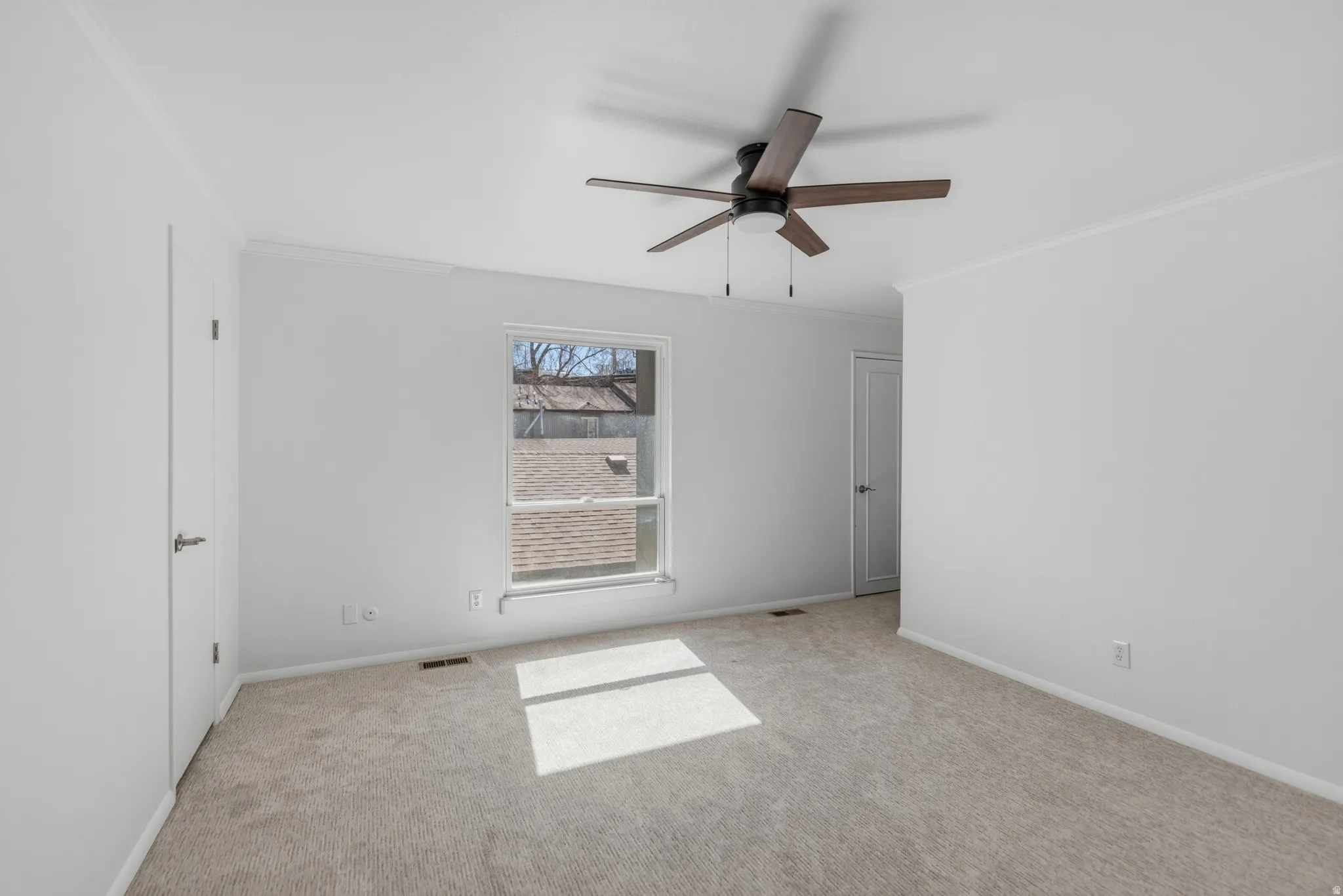 Empty room with crown molding, carpet flooring, and ceiling fan
