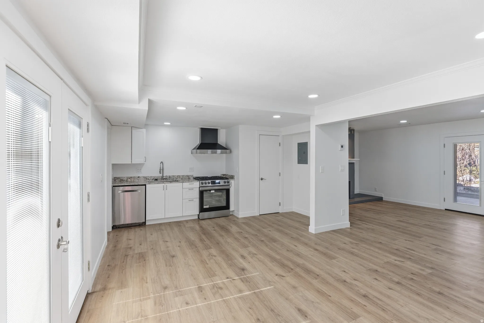 Kitchen with recessed lighting, stainless steel appliances, white cabinetry, light wood-type flooring, and open floor plan