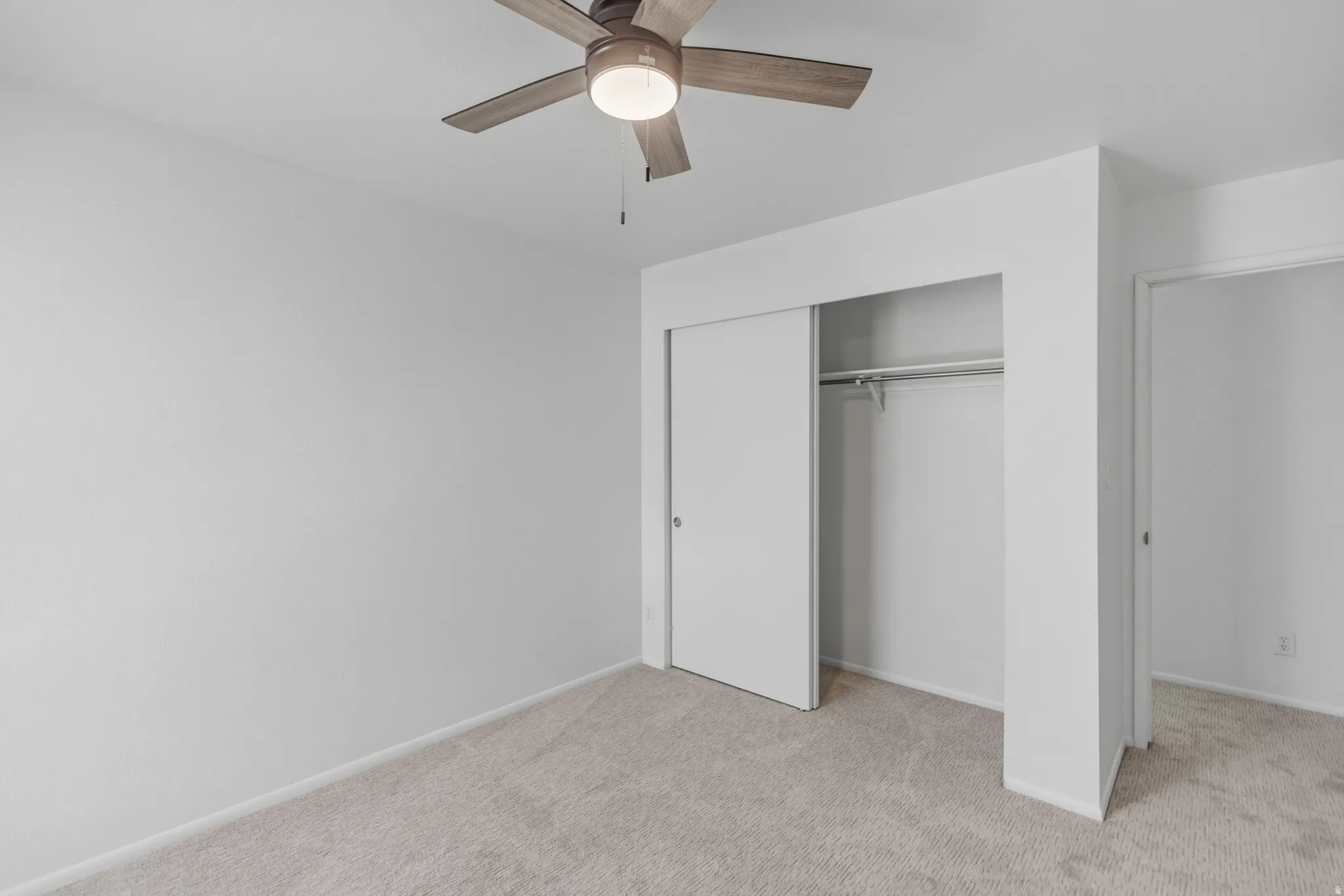 Unfurnished bedroom with light carpet, ceiling fan, and a closet
