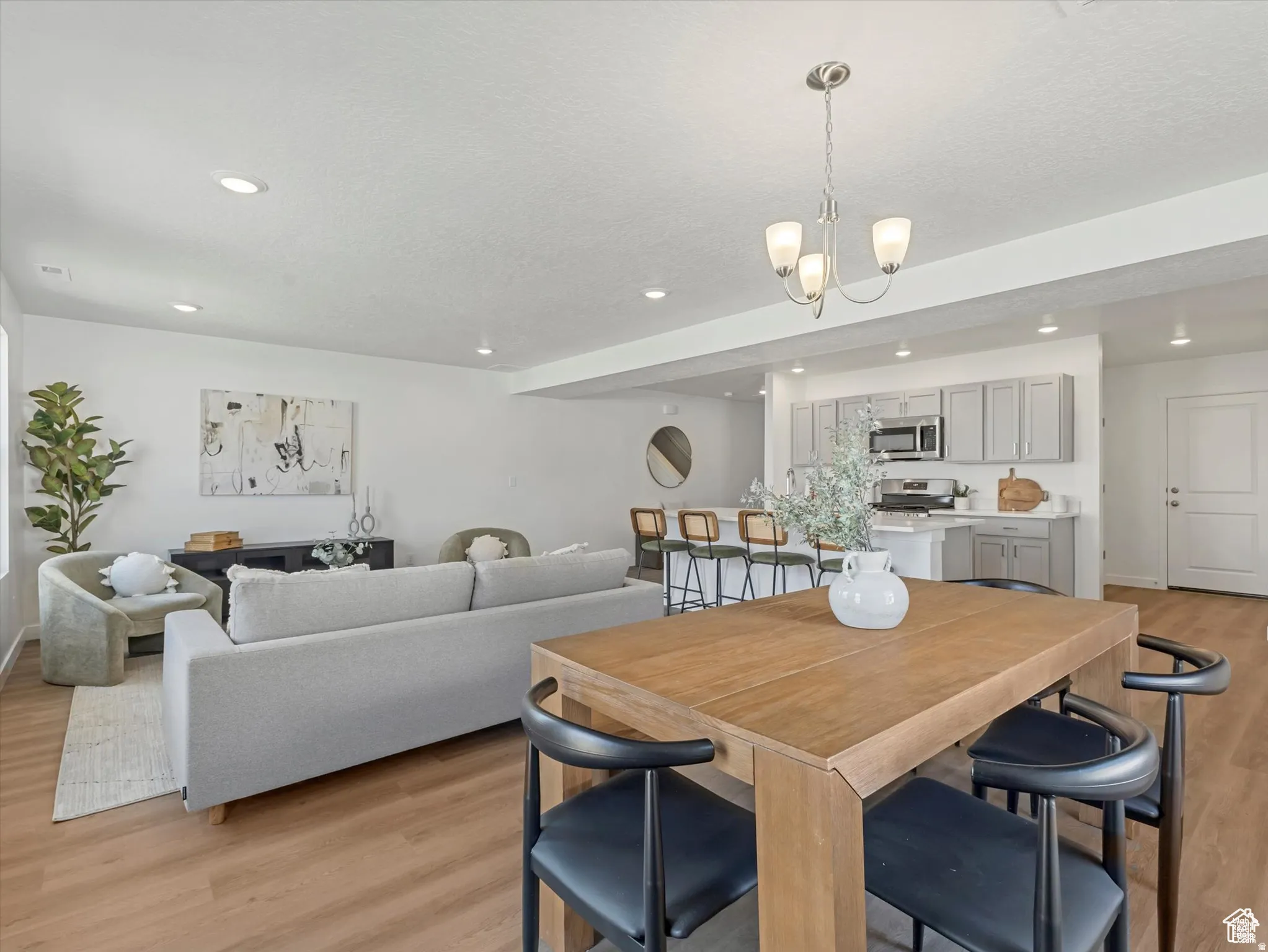 Dining space featuring light wood-style flooring, hanging lights, and a textured ceiling