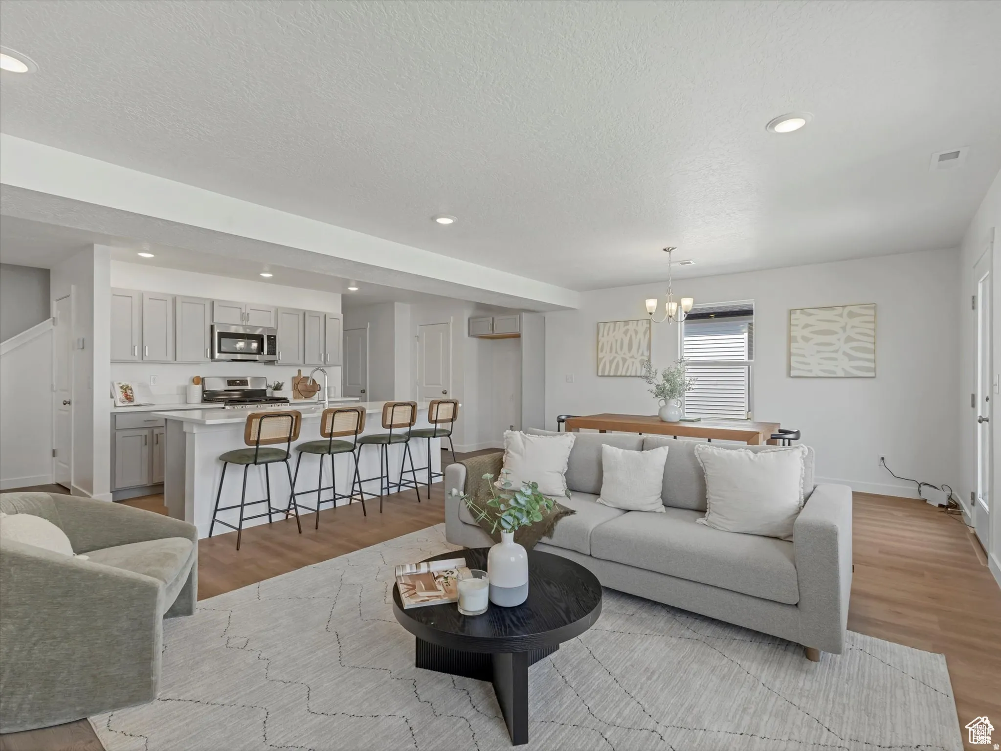 Living room with light wood-style floors, a chandelier, and a textured ceiling