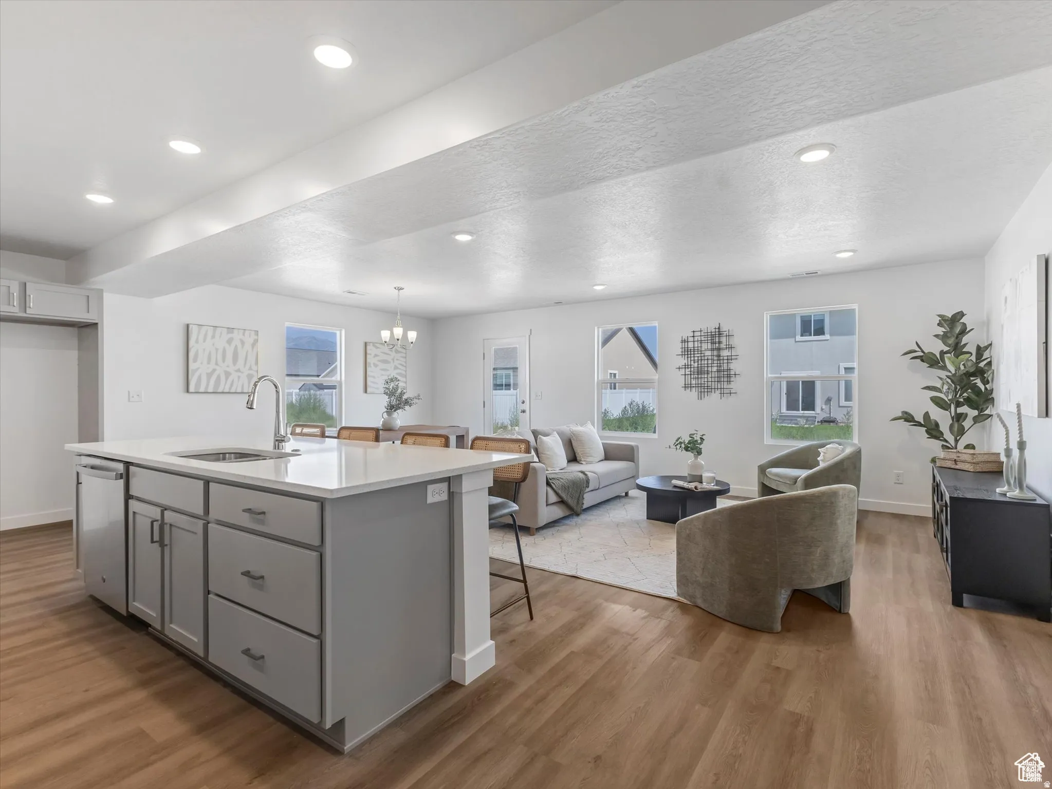 Kitchen featuring gray cabinetry, light wood-type flooring, suspended lighting, open floor plan, and a textured ceiling