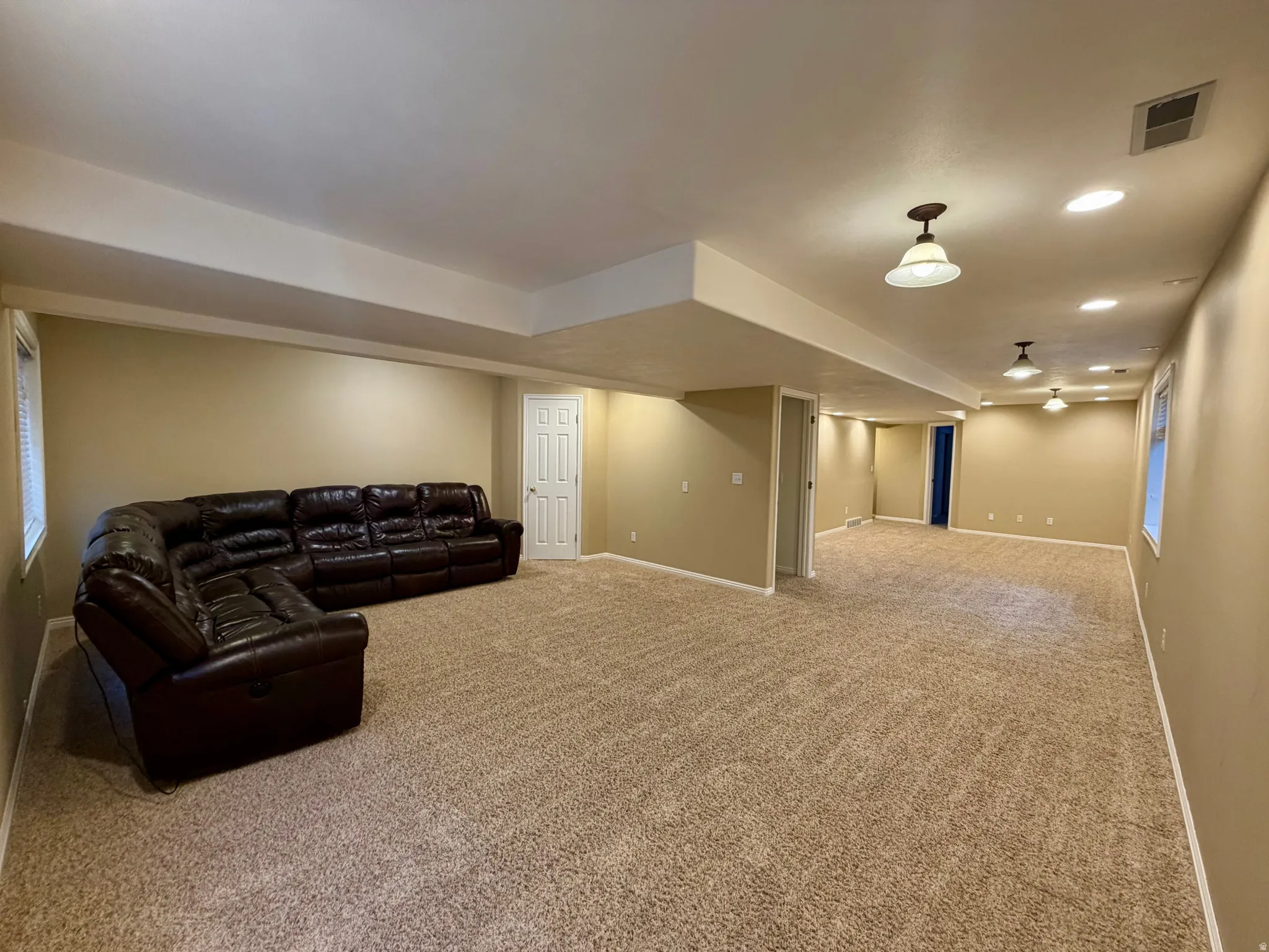 Large family room provides the perfect space with light carpet and recessed lighting