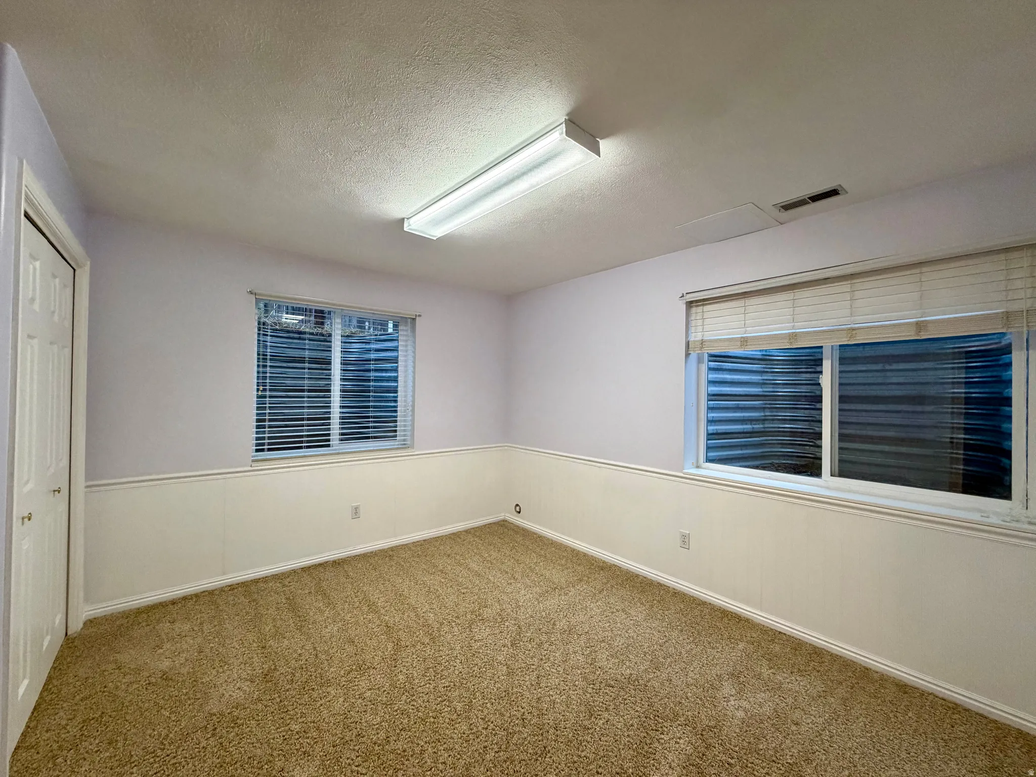Light bedroom featuring two large windows, a closet and  a wainscoted wall