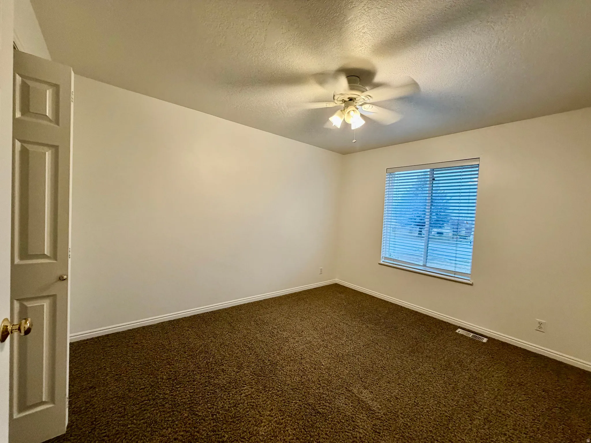 Bedroom with closet dark carpet, ceiling fan, and a textured ceiling