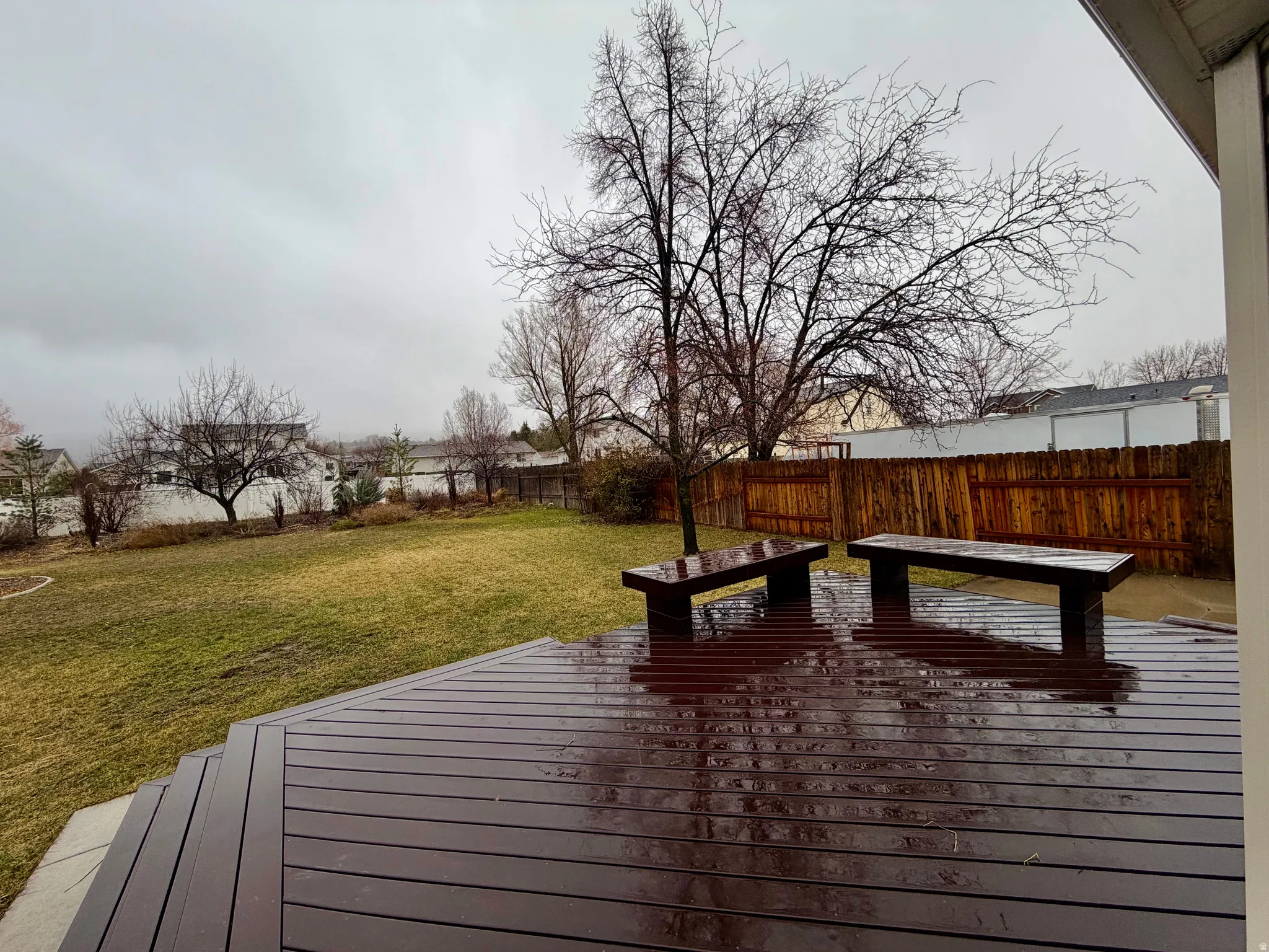 View of track deck with built it benches, landscaped yard,  and fenced backyard