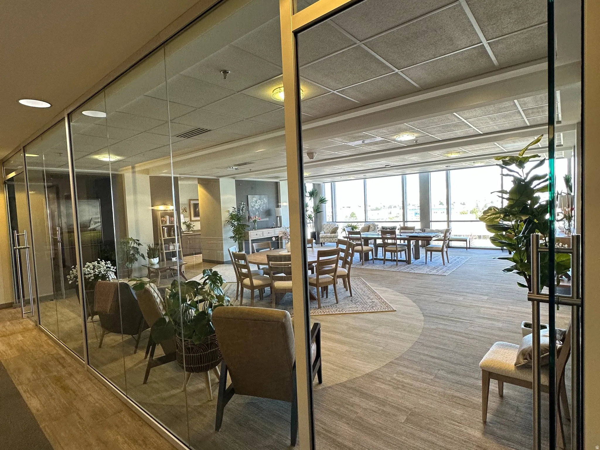Break area with a drop ceiling, wood finished floors, and expansive windows