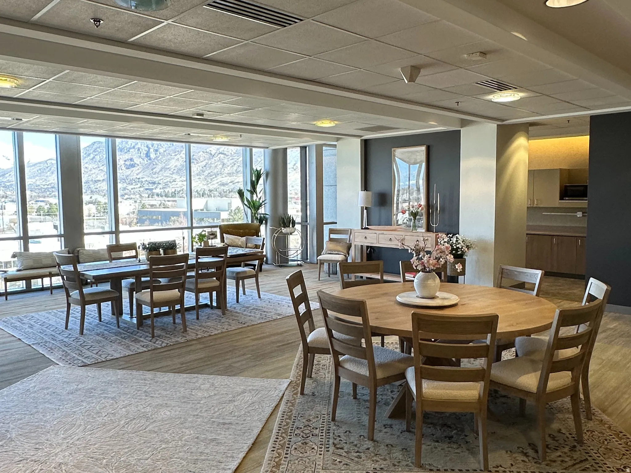 Break area with a drop ceiling, wood finished floors, and expansive windows