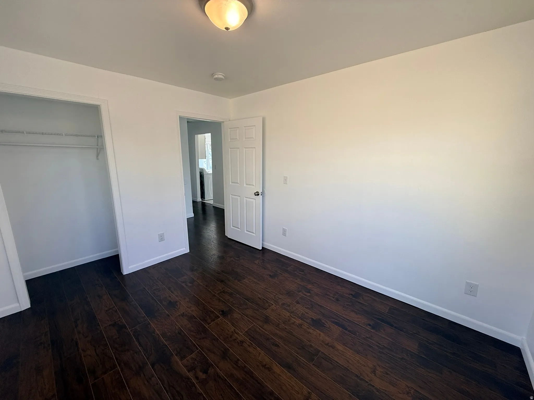 Unfurnished bedroom featuring dark wood-style flooring and a closet