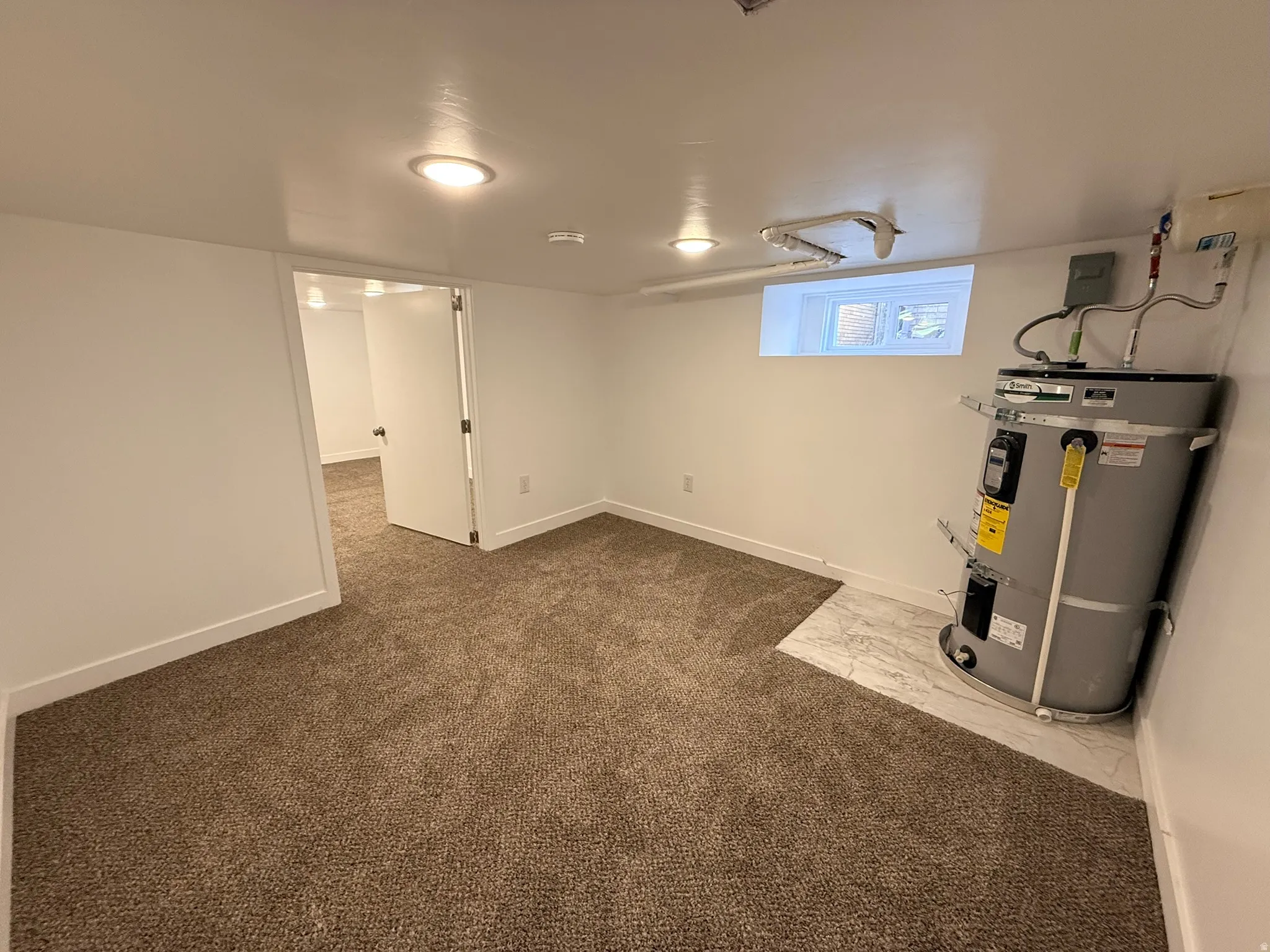 Below grade area with water heater and dark colored carpet