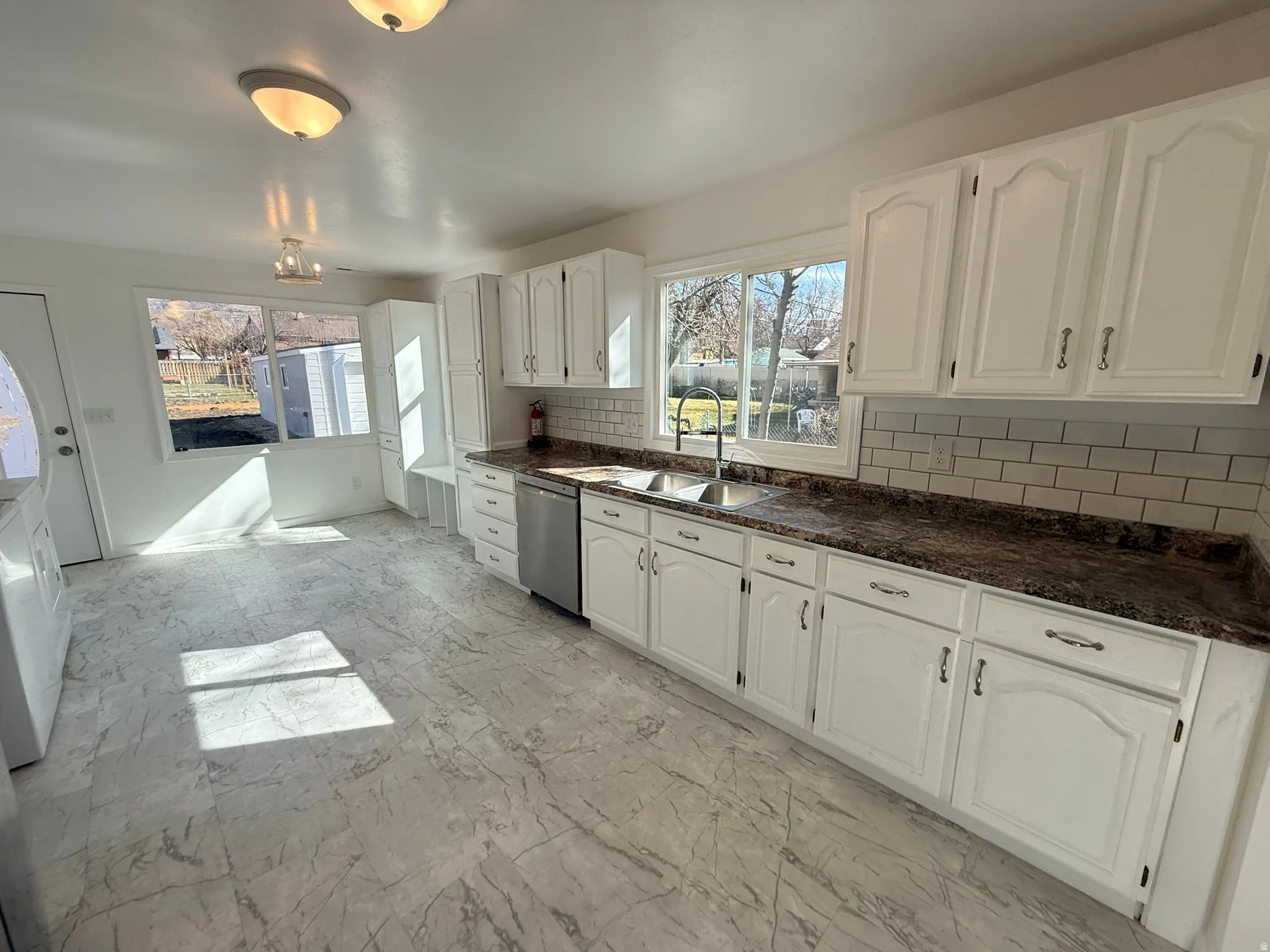 Kitchen featuring white cabinetry, decorative backsplash, plenty of natural light, and stainless steel dishwasher