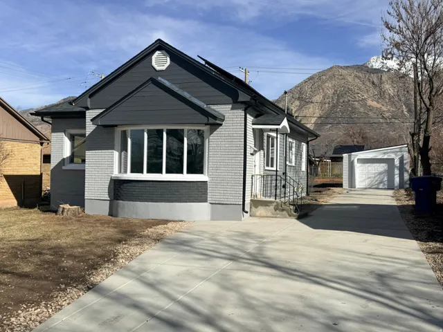 View of front of home with brick siding, an outbuilding, concrete driveway, and a garage