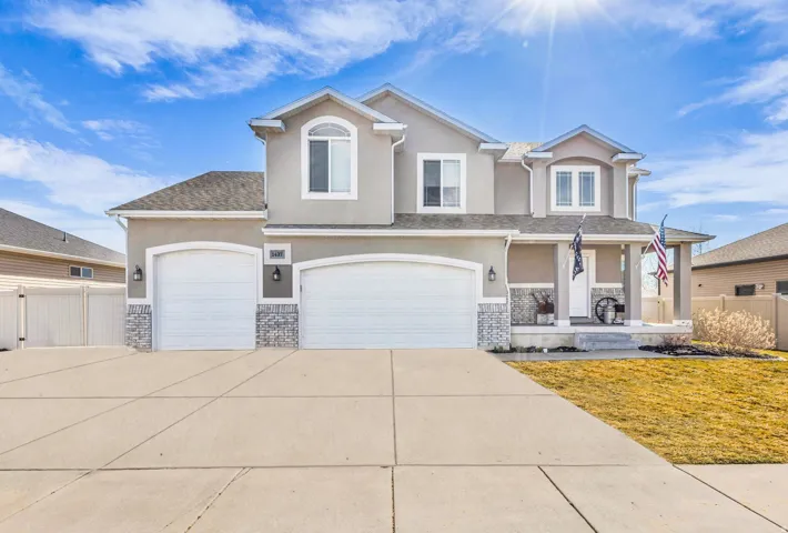View of front of house with stucco siding, covered porch, concrete driveway, and a garage