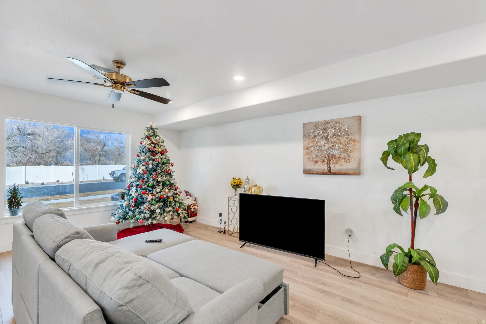 Living room with ceiling fan, light wood-style floors, and recessed lighting