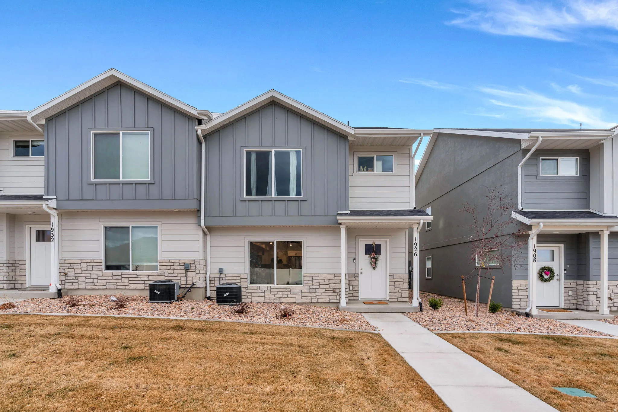 View of front of house with stone siding, a front yard, and board and batten siding