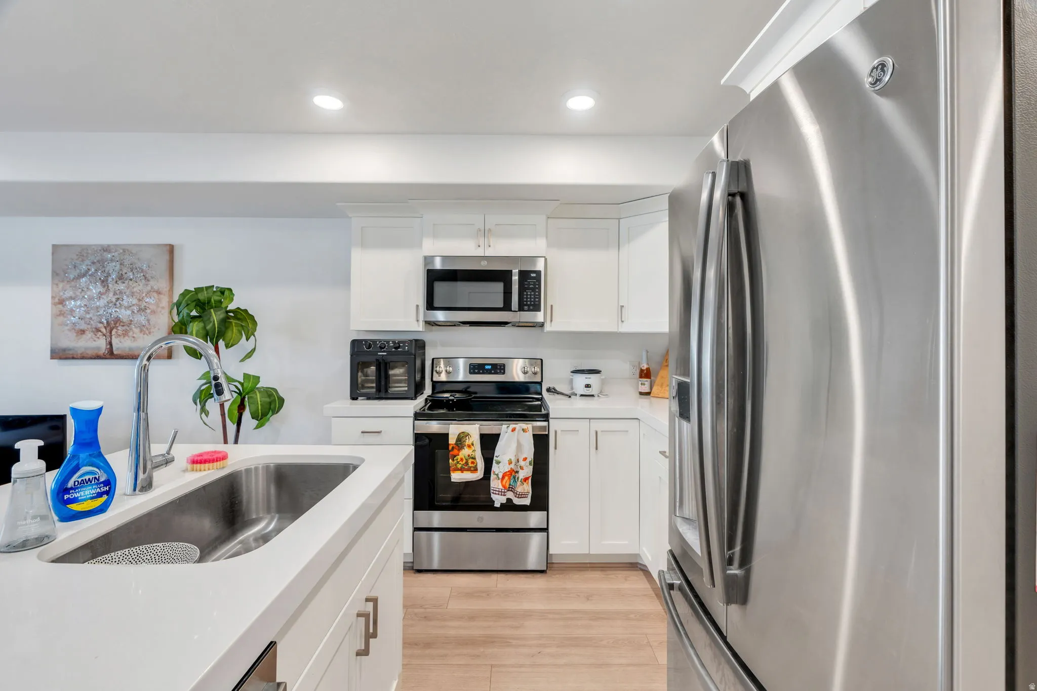 Kitchen featuring stainless steel appliances, white cabinets, light wood-style floors, and recessed lighting
