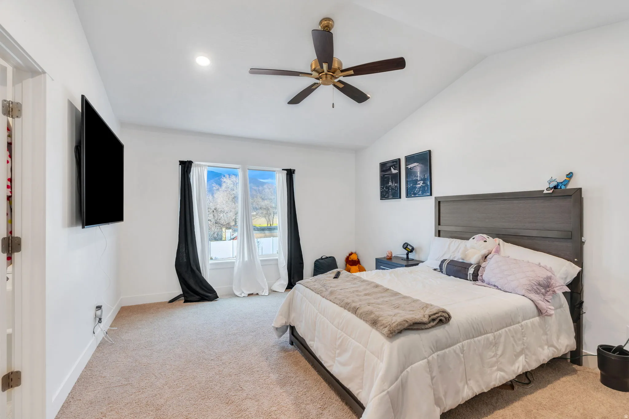 Bedroom featuring light carpet, a ceiling fan, and vaulted ceiling
