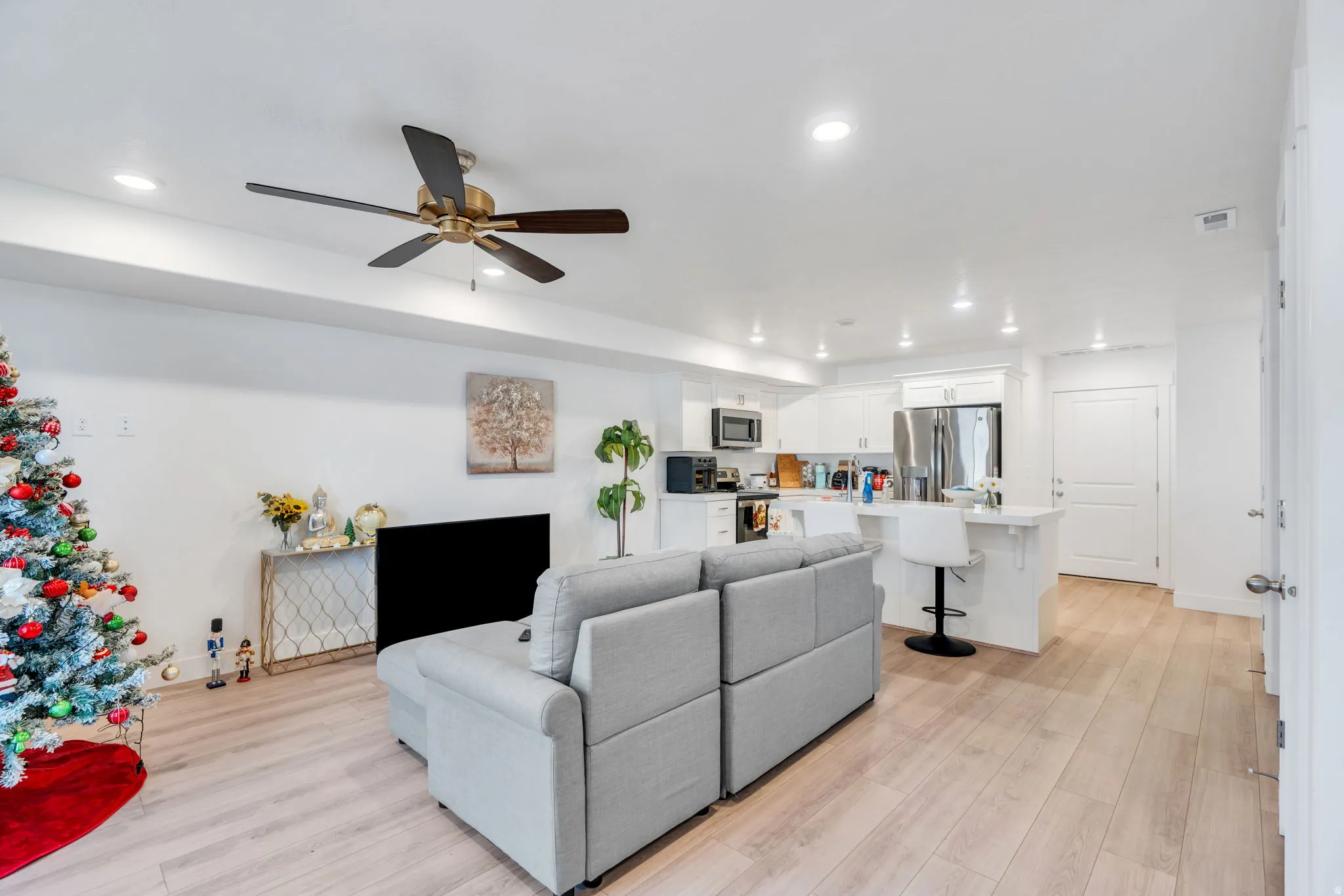 Living area with light wood-type flooring, a ceiling fan, and recessed lighting