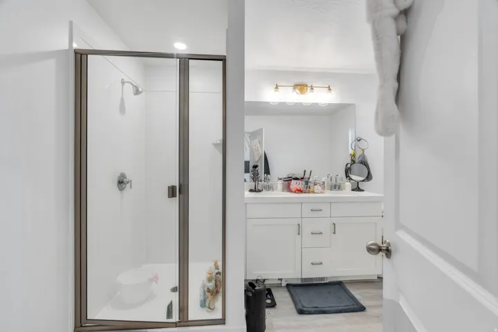 Full bath with double vanity, a stall shower, and light wood-type flooring