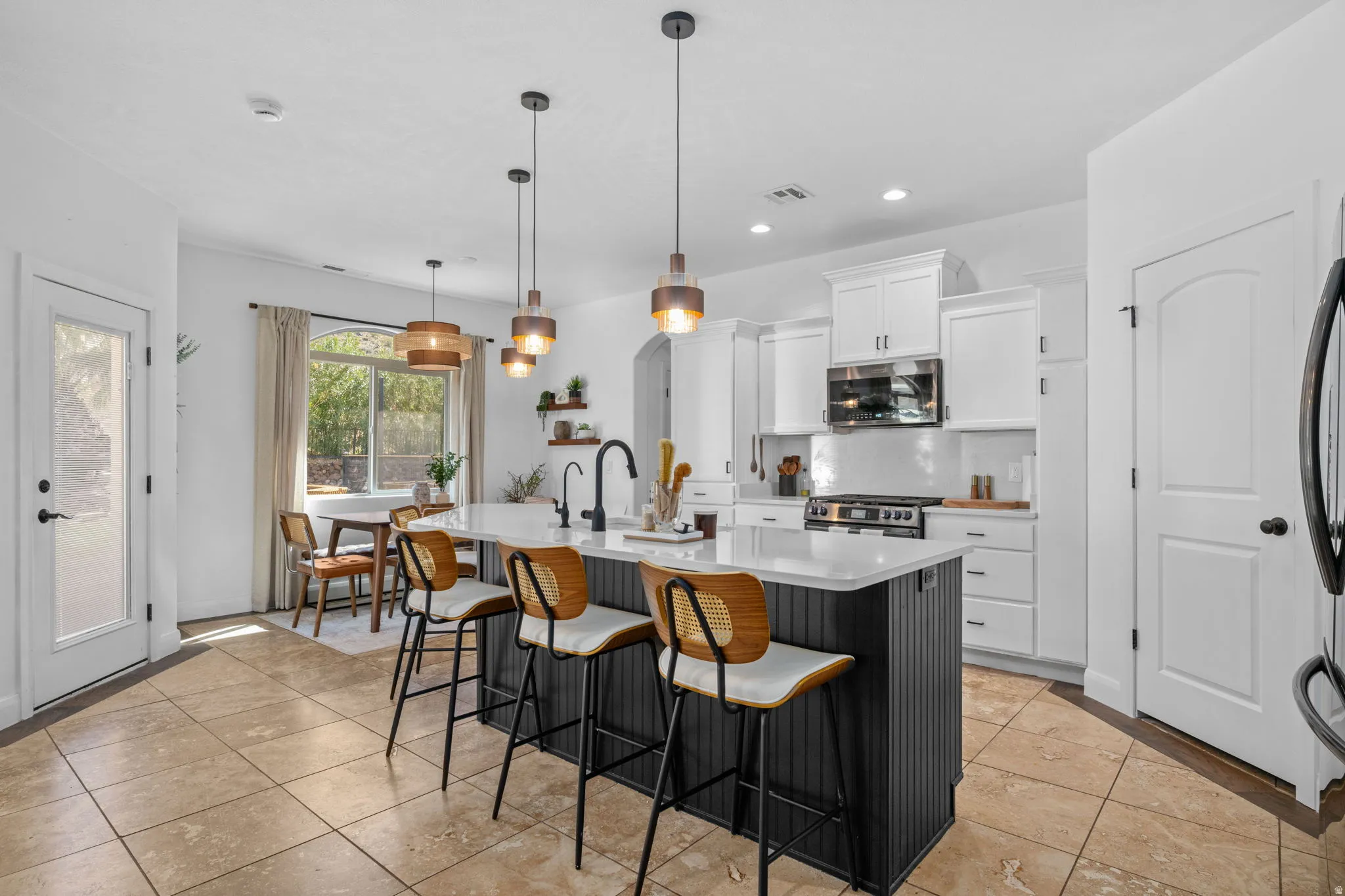 Kitchen featuring a kitchen breakfast bar, a center island with sink, tasteful backsplash, dual tone cabinetry, and stainless steel appliances