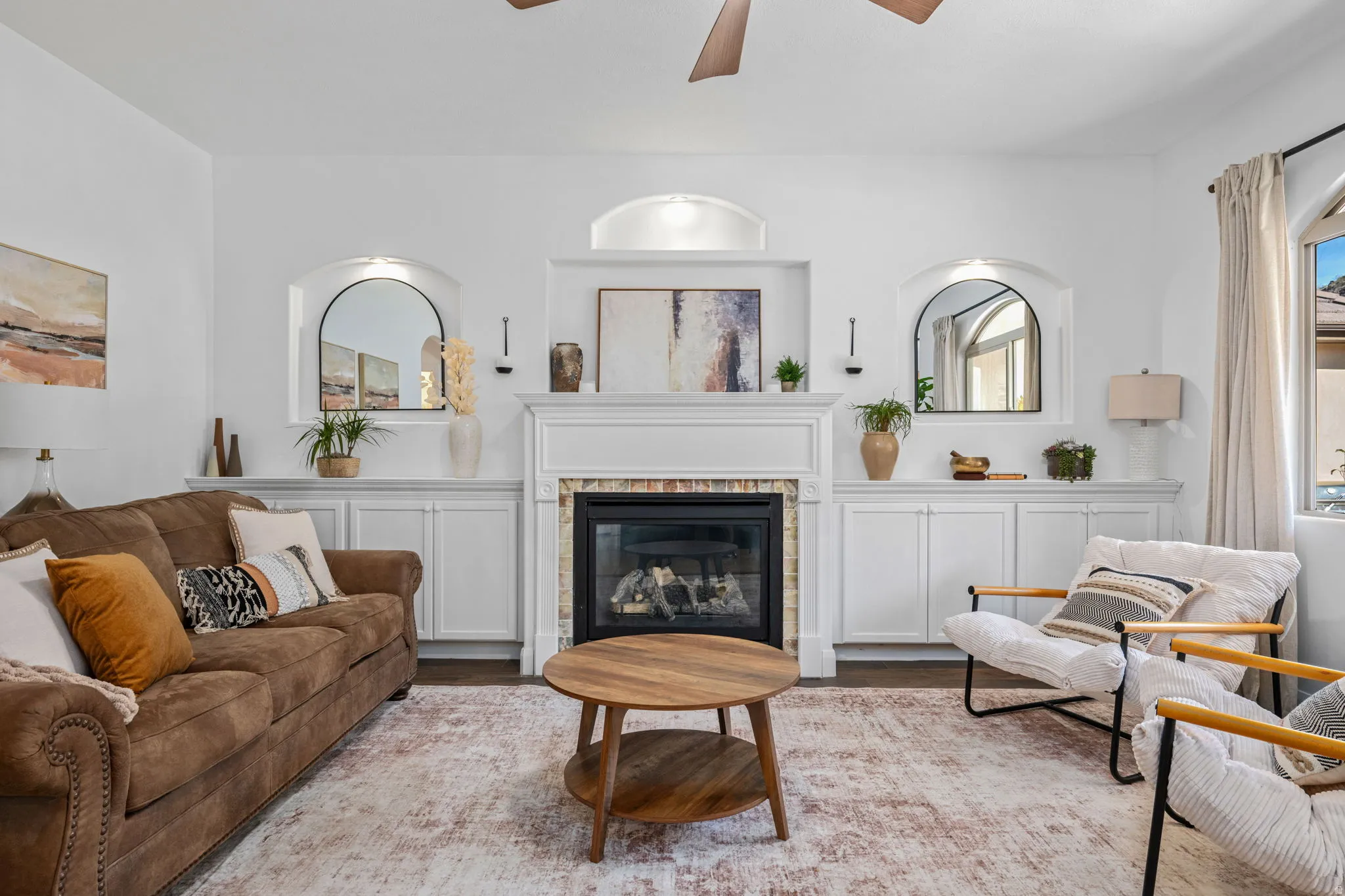 Living room with a glass covered fireplace, a ceiling fan, and wood finished floors