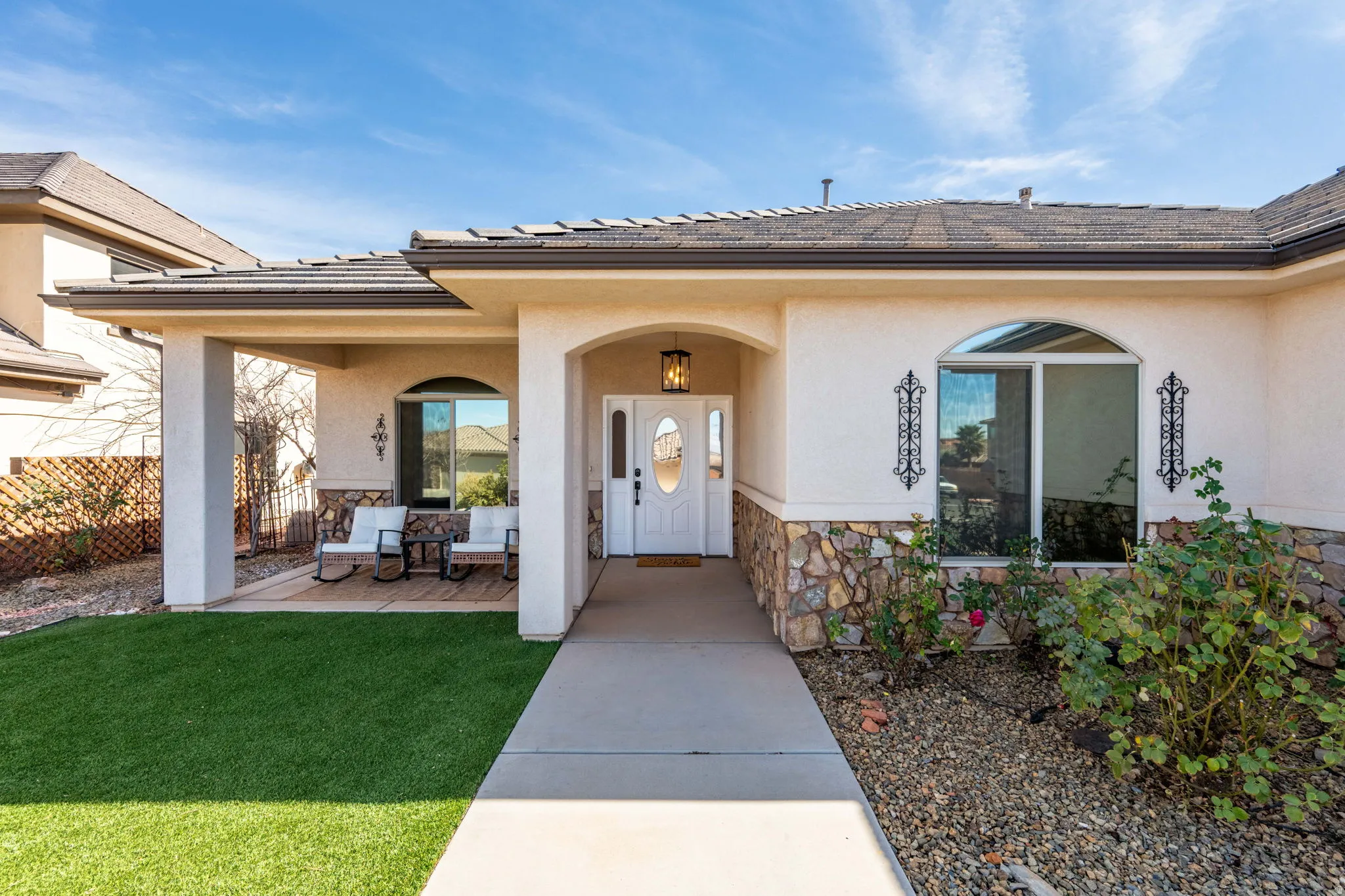 Property entrance featuring stone siding, stucco siding, covered porch, and a tiled roof