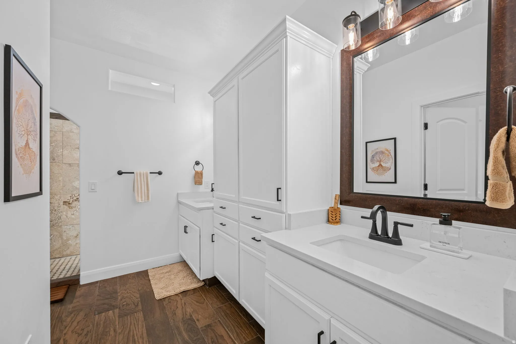 Full bath featuring two vanities, dark wood-style floors, and walk in shower