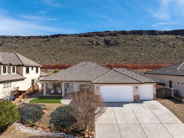 View of front facade featuring a garage, concrete driveway, stucco siding, stone siding, and a tile roof