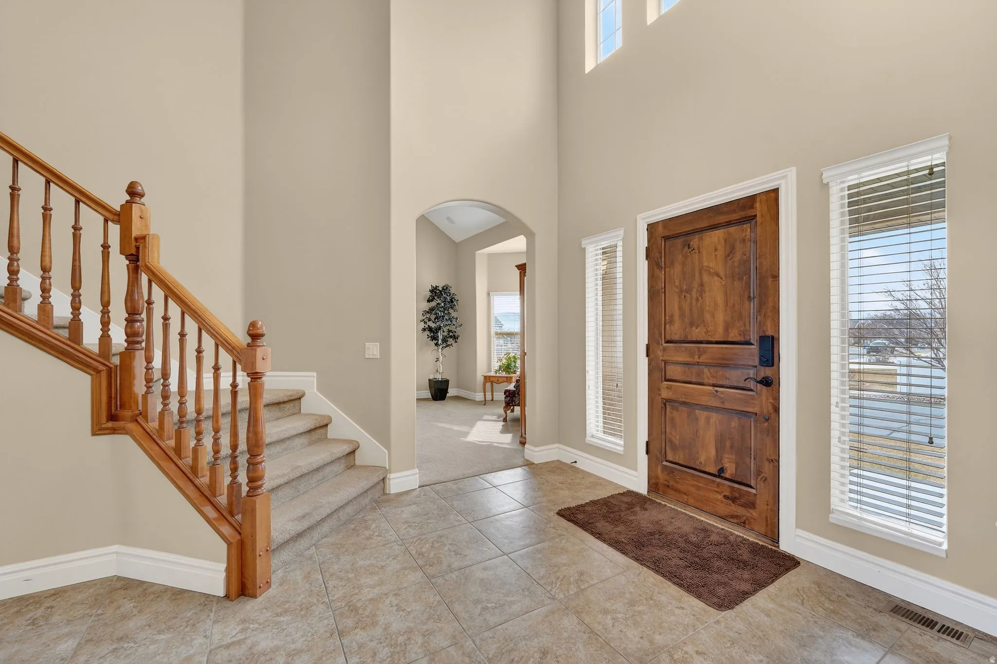 Entrance foyer featuring arched walkways, a high ceiling, and light tile patterned flooring