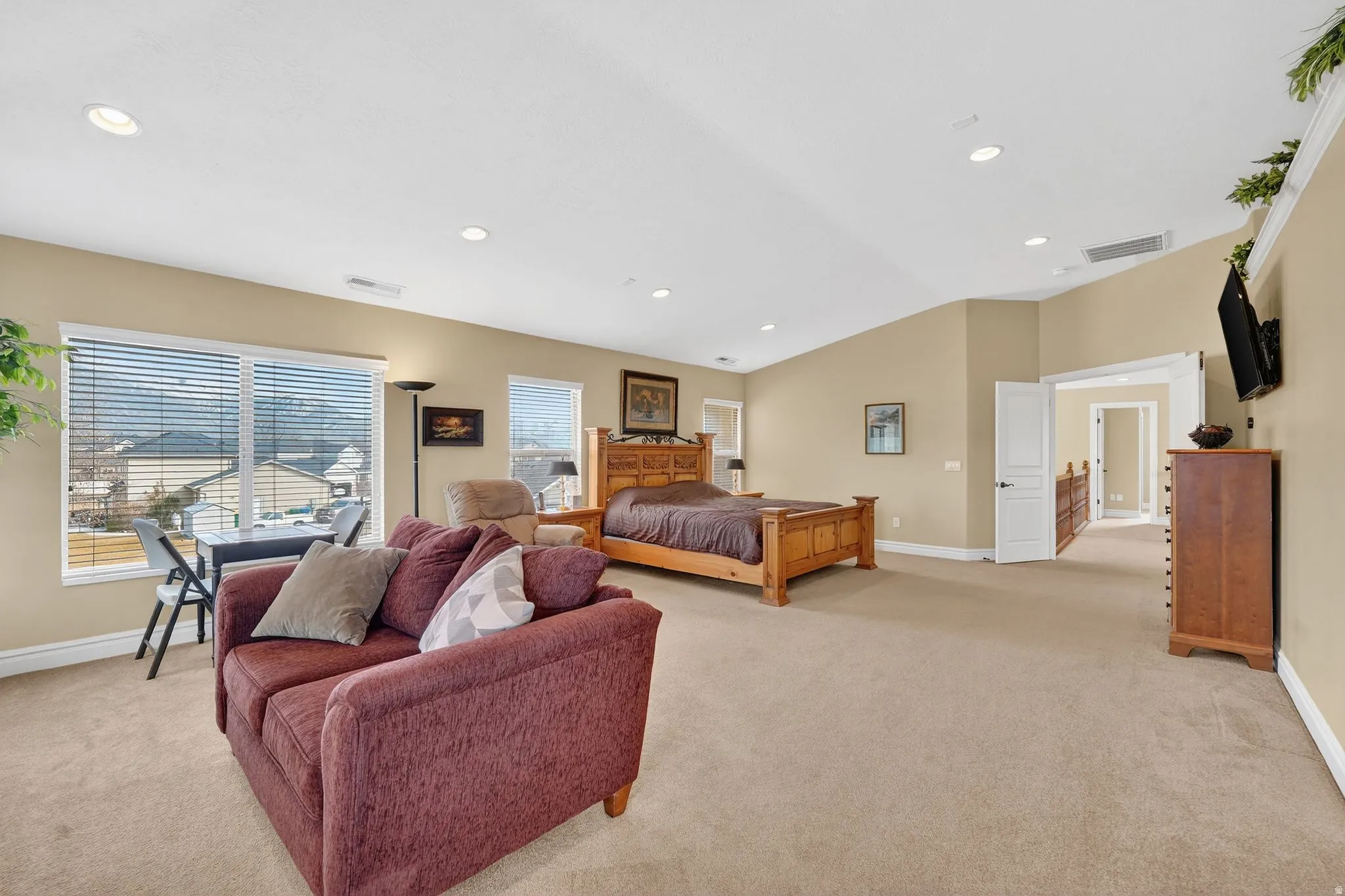 Bedroom with light colored carpet, lofted ceiling, and recessed lighting