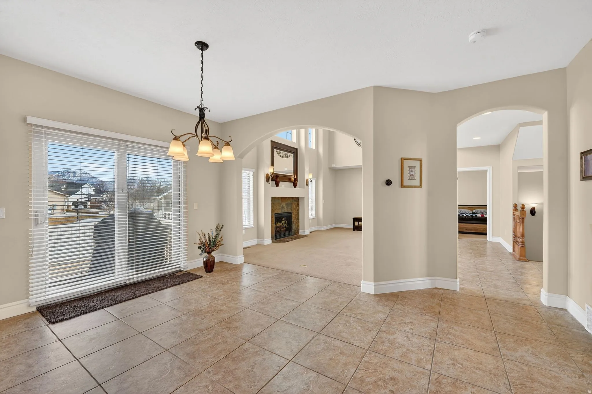 Unfurnished dining area featuring arched walkways, a tile fireplace, light tile patterned floors, and suspended lighting
